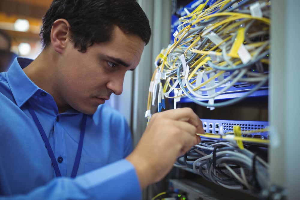 Technician checking cables in a rack mounted server in server room-1